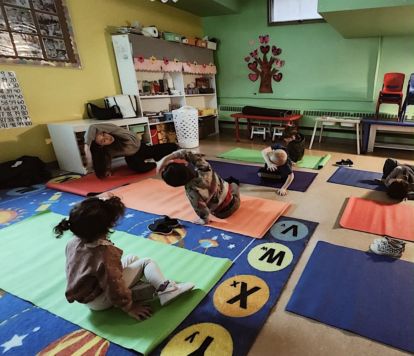 Young children practicing yoga poses on colourful mats at a daycare